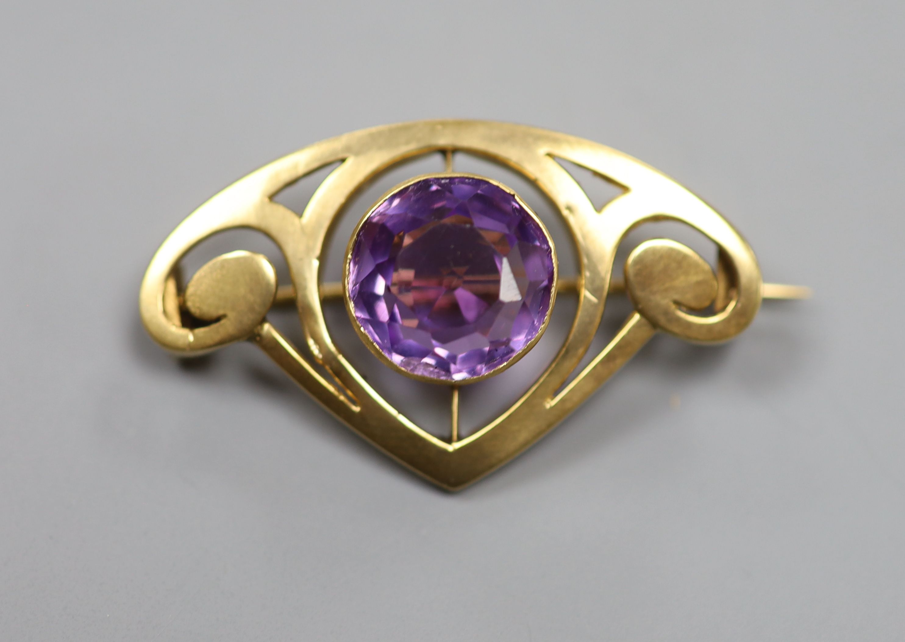 An early 20th century Art Nouveau yellow metal and amethyst set stylised brooch